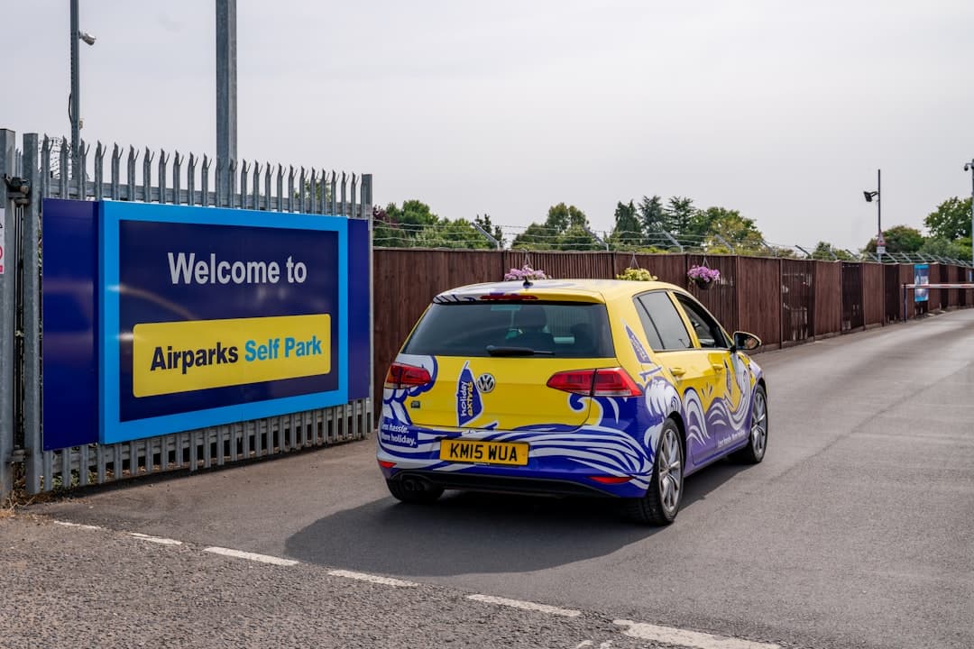 A yellow car with colorful graphics drives towards an entrance. — Photo by Holiday Extras on Unsplash
