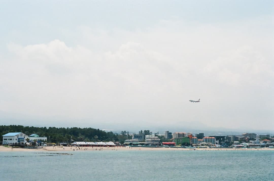 an airplane is flying over a beach with houses — Photo by Finn on Unsplash