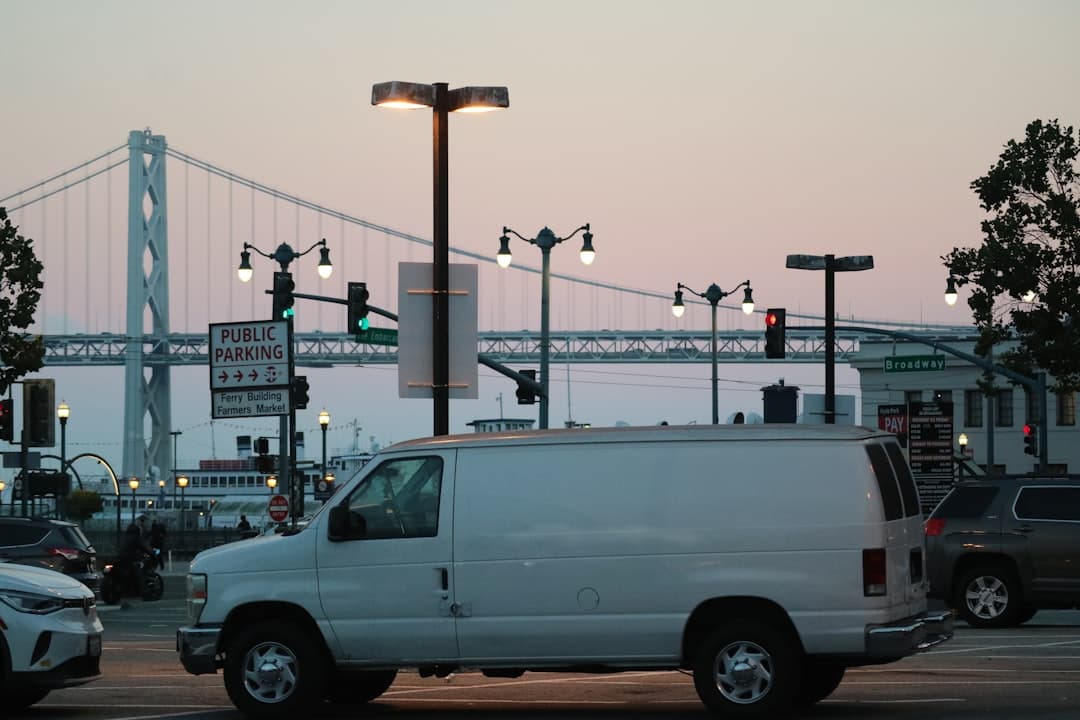 a white van driving down a street next to a bridge — Photo by Vincent Y @USA on Unsplash