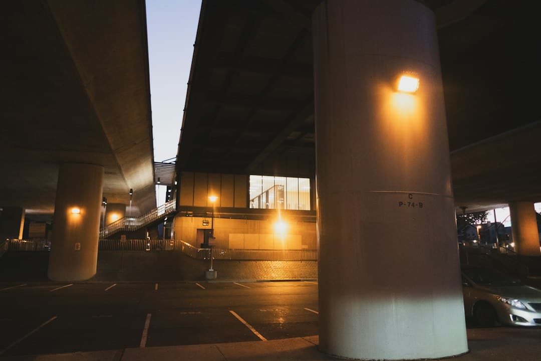 A parking garage with lights on and a car parked underneath — Photo by Fabio Sasso on Unsplash