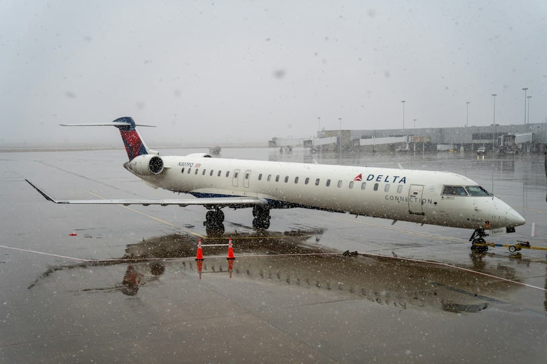 a delta airplane is parked on a wet runway — Photo by Charles Shaffer on Unsplash