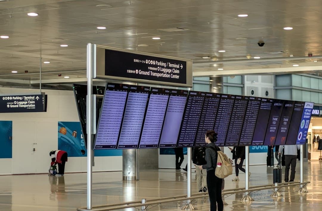 A person with a backpack looking at a large airport flight information display — Photo by Preston A Larimer on Unsplash