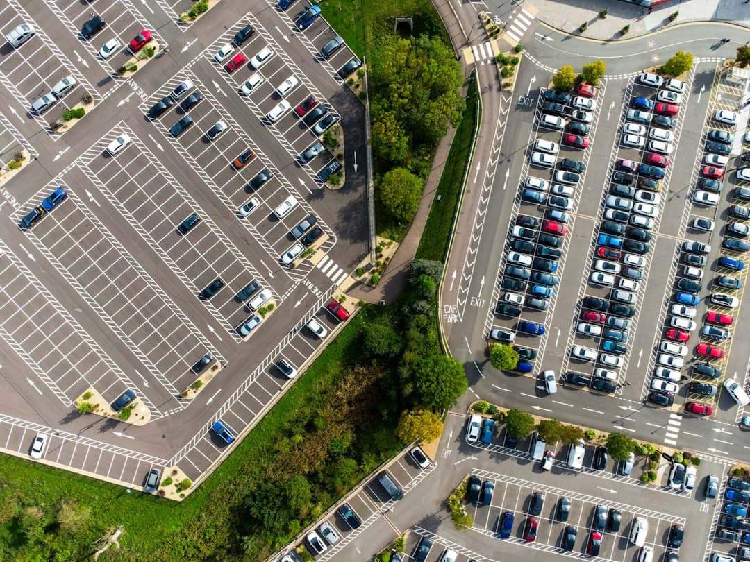 an aerial view of a parking lot with cars parked in it — Photo by Benjamin Cheng on Unsplash
