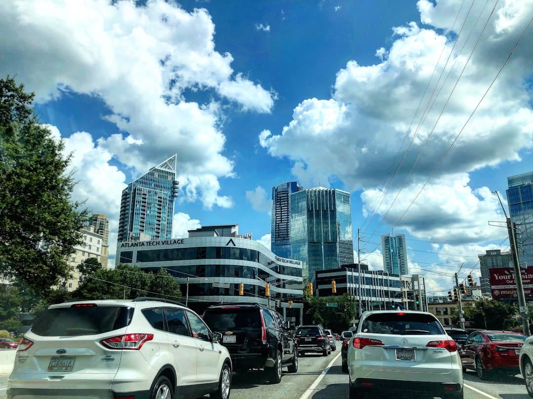 different vehicles on road viewing city with high-rise buildings under white and blue skies — Photo by Tayshawn Royster on Unsplash