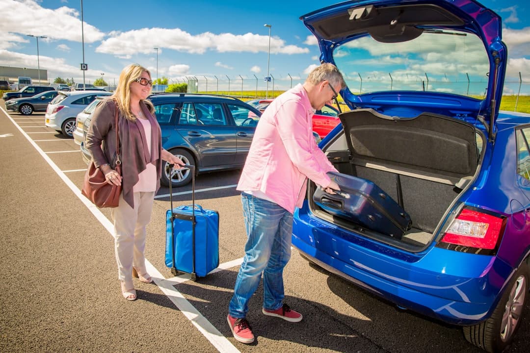 Couple loading luggage into a blue car — Photo by Holiday Extras on Unsplash