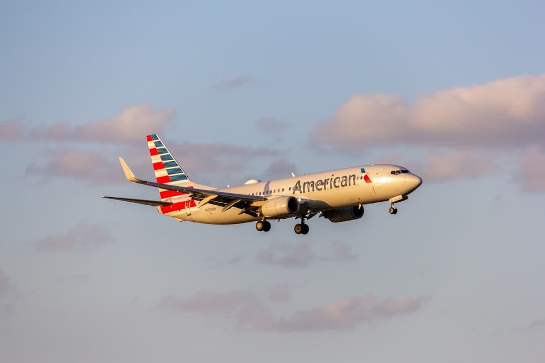 A large passenger jet flying through a blue sky — Photo by Izyan Sultanali on Unsplash