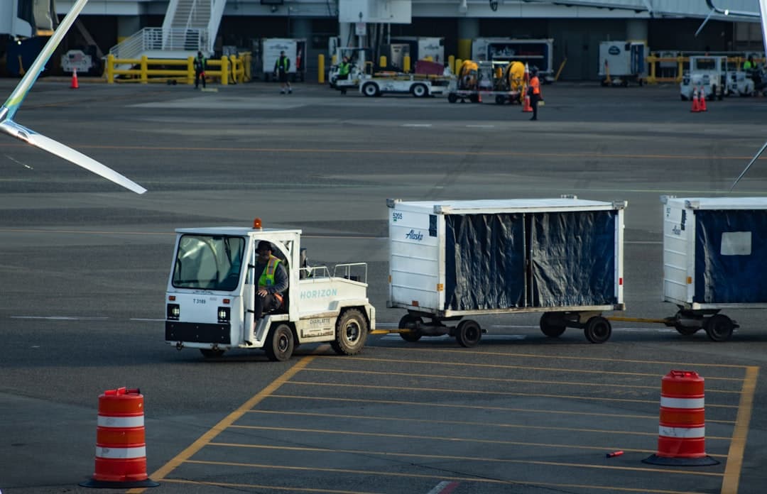 Tug pulls baggage carts across airport tarmac — Photo by Jay Heike on Unsplash
