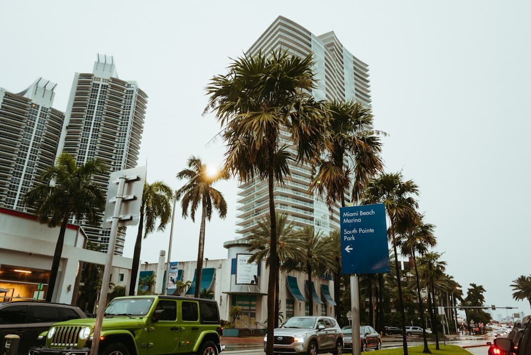 a green jeep driving down a street next to tall buildings — Photo by Daniel on Unsplash