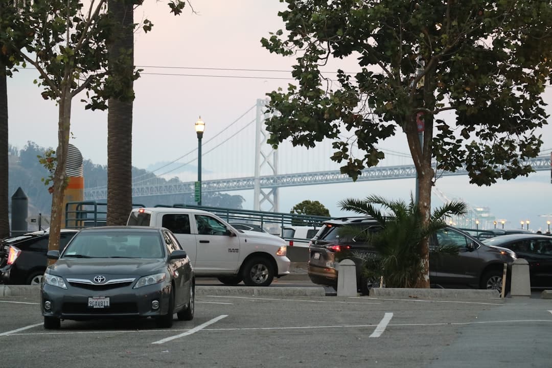cars parked in a parking lot with a bridge in the background — Photo by Vincent Y @USA on Unsplash