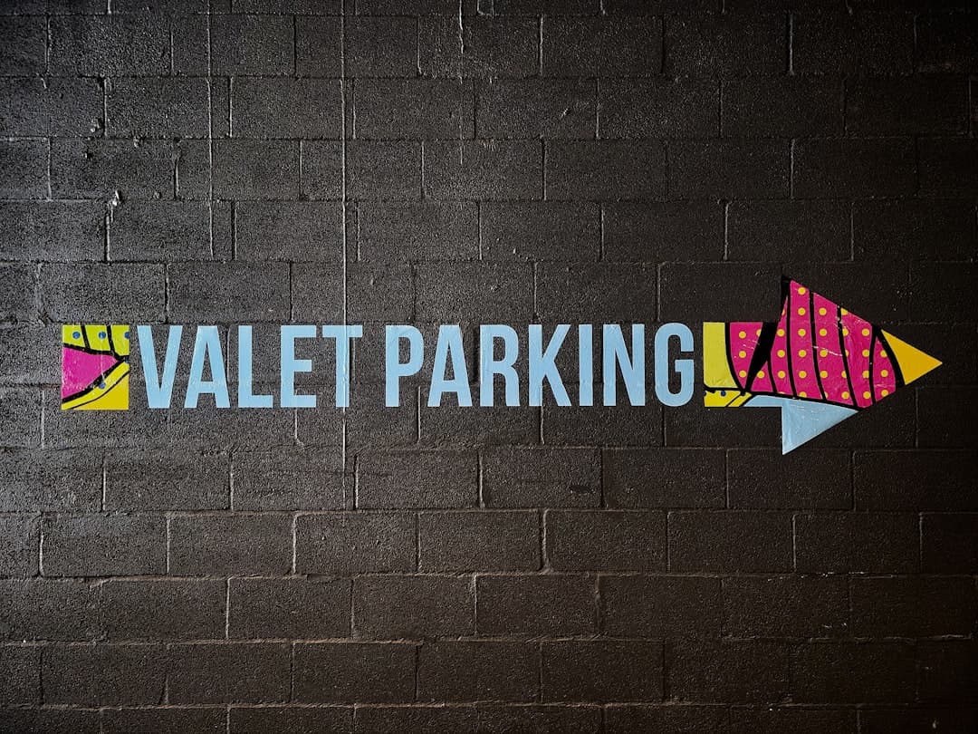 a painted sign on a brick wall that says valet parking — Photo by George Pagan III on Unsplash