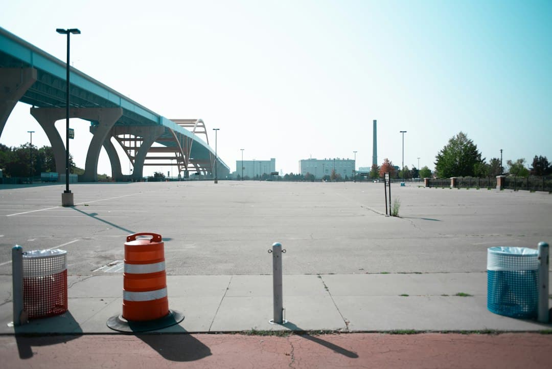 an empty parking lot with a bridge in the background — Photo by Zach Lisko on Unsplash