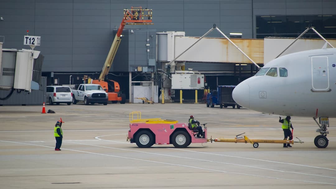 Airport workers guide airplane with tow tractor — Photo by Jonathan Marchant on Unsplash