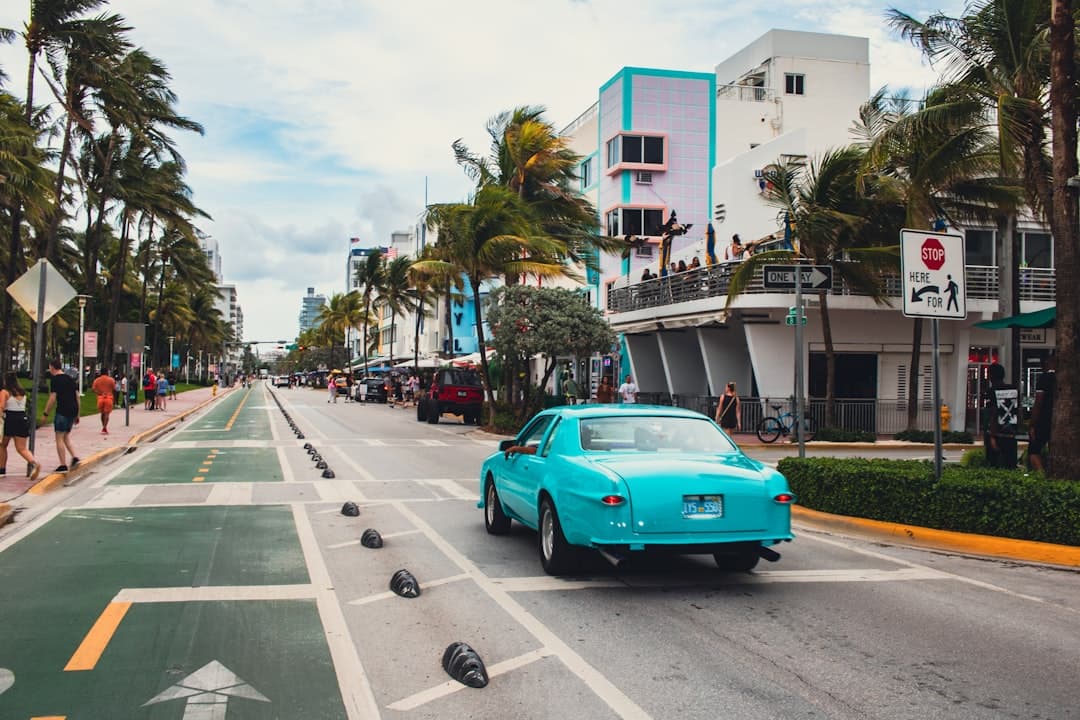A blue car driving down a street next to palm trees — Photo by Zoshua Colah on Unsplash
