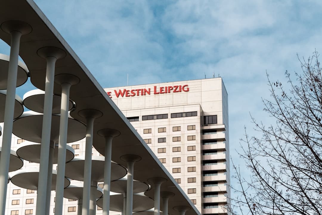 A tall white building with a red sign on top of it — Photo by Ben Kupke on Unsplash