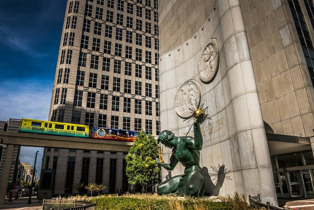 a statue in front of a building with a train passing by — Photo by Richard Hedrick on Unsplash