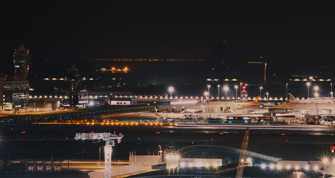 an airport at night with lights on the runway — Photo by Sugarman Joe on Unsplash