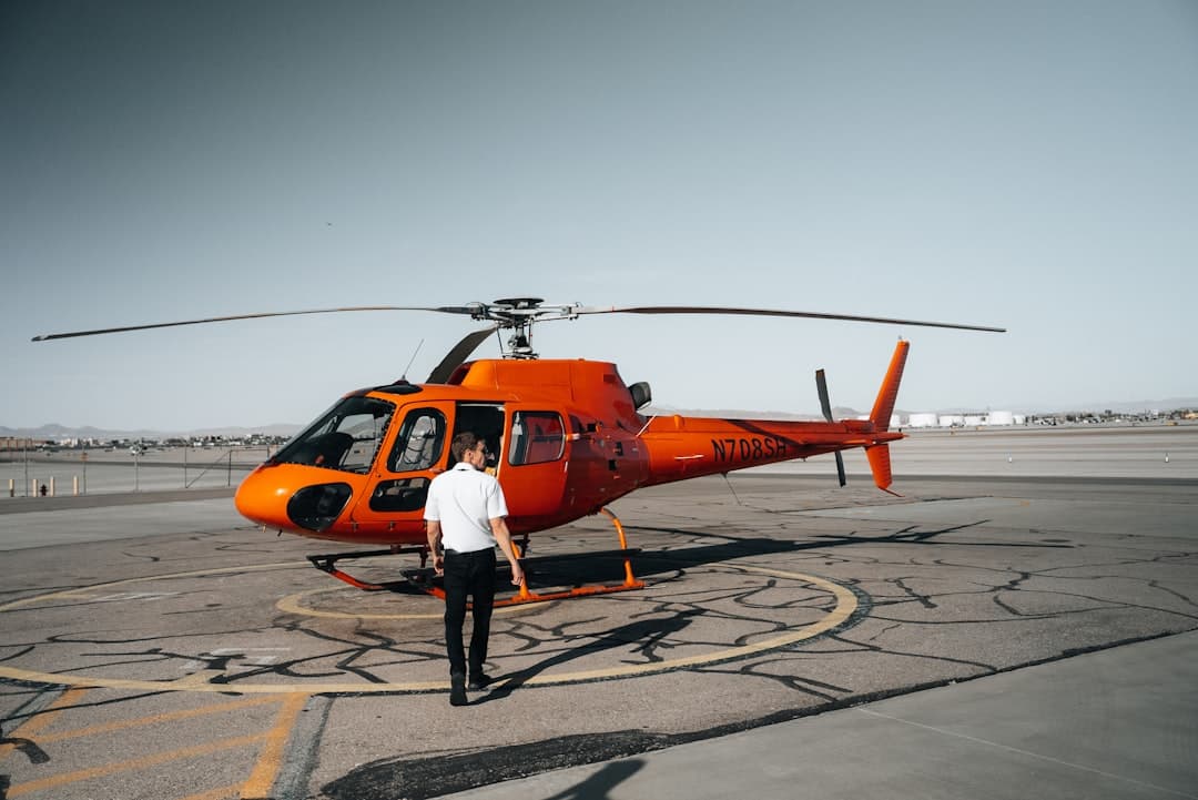 a man standing in front of a helicopter on a runway — Photo by Nejc Soklič on Unsplash