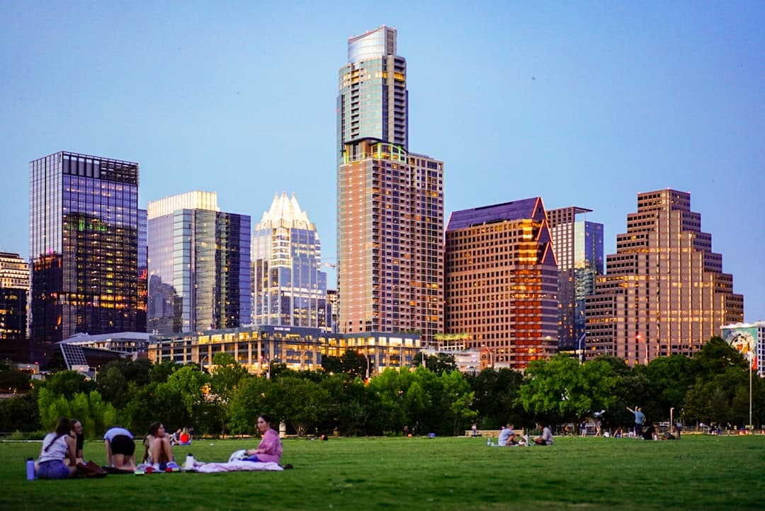 people sitting on green grass field near city buildings during daytime — Photo by Megan Bucknall on Unsplash