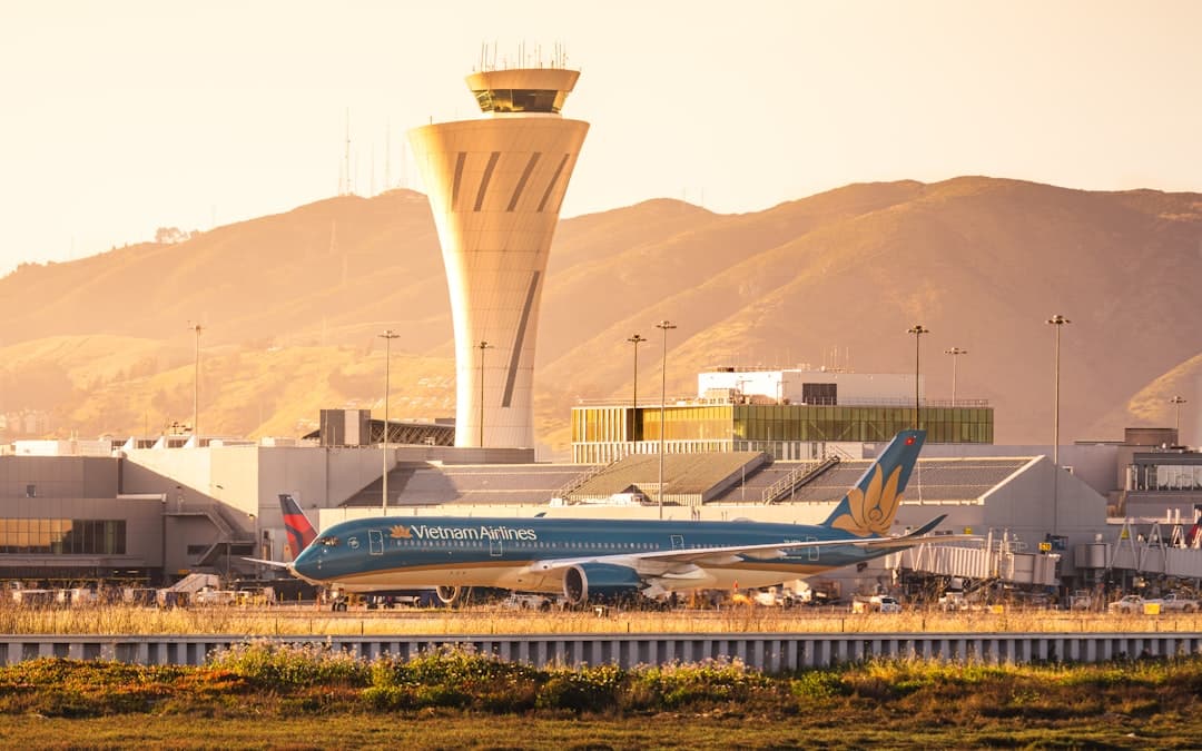 An airplane is at the airport near the control tower. — Photo by Hieu on Unsplash