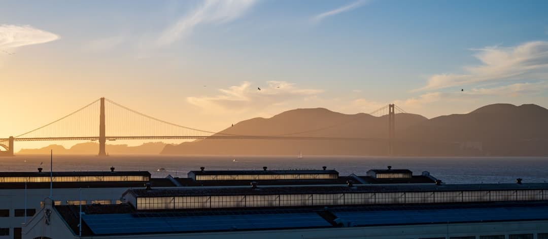 Golden gate bridge at sunset with distant hills. — Photo by Thomas Lamars on Unsplash