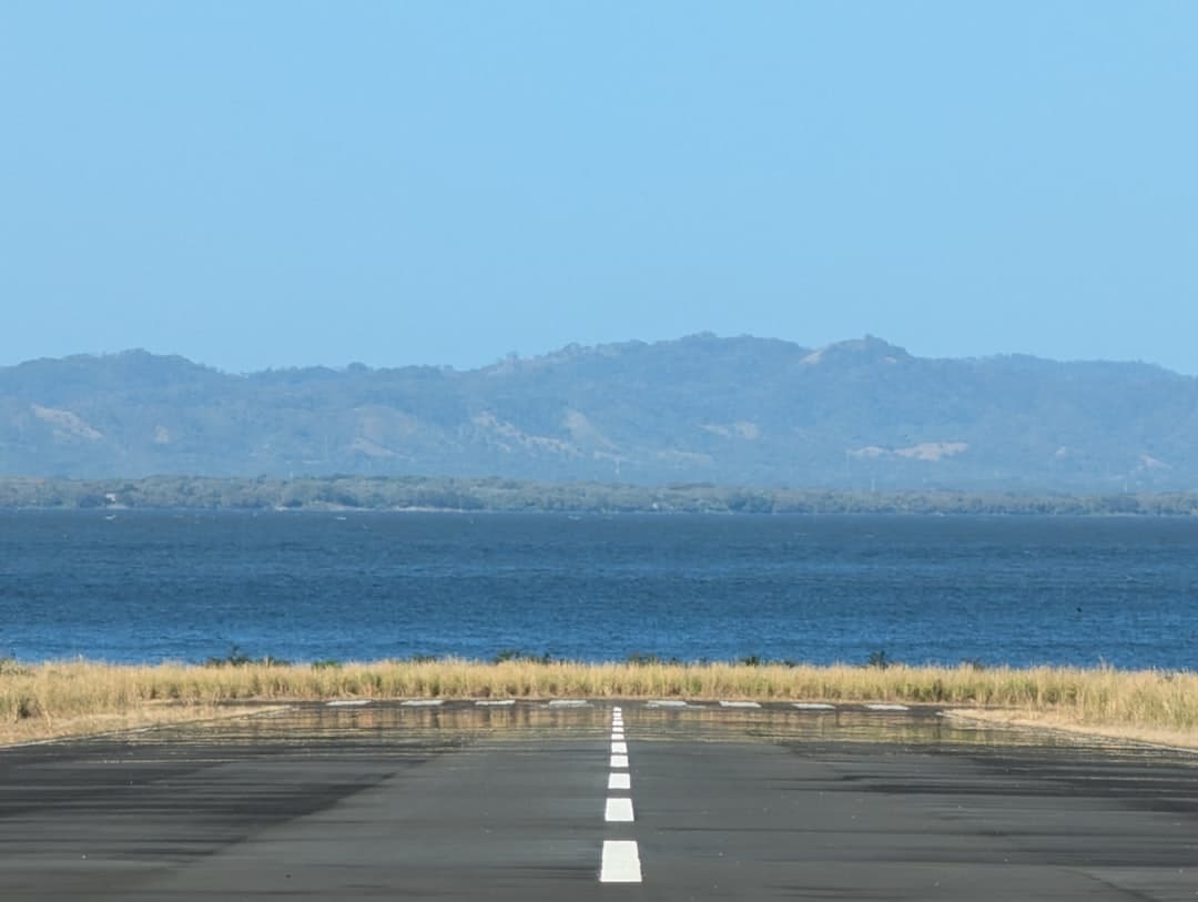 An empty runway stretches towards distant mountains and sea. — Photo by Brandon Jarquin on Unsplash