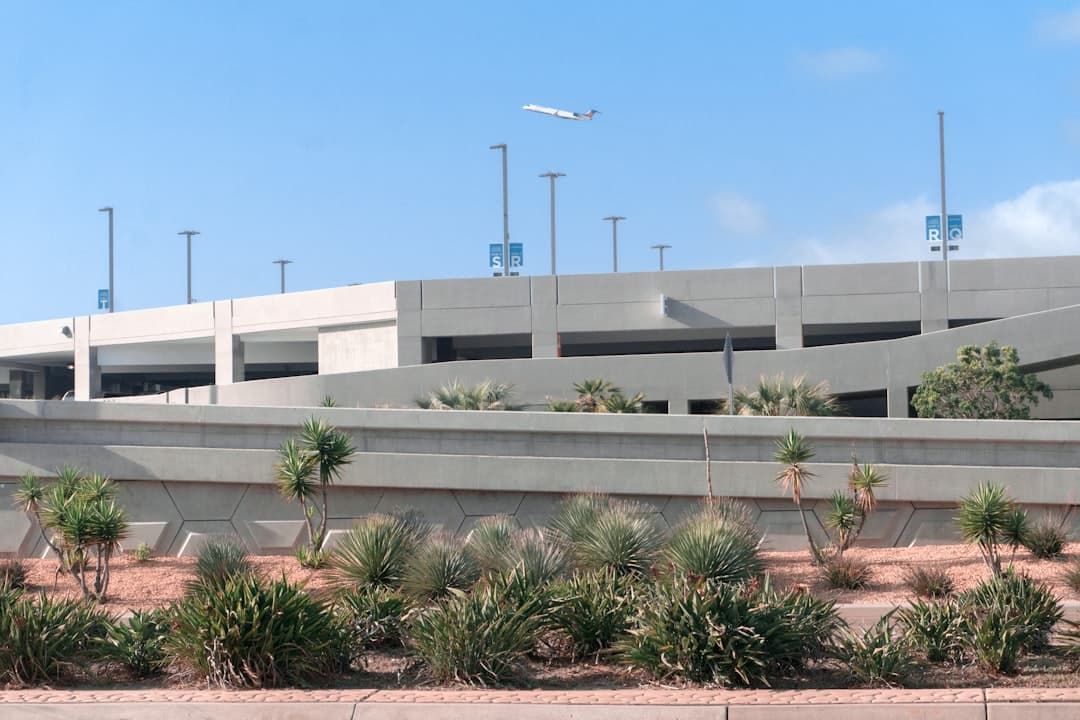 white concrete building near green palm tree under blue sky during daytime — Photo by Anton Mishin on Unsplash