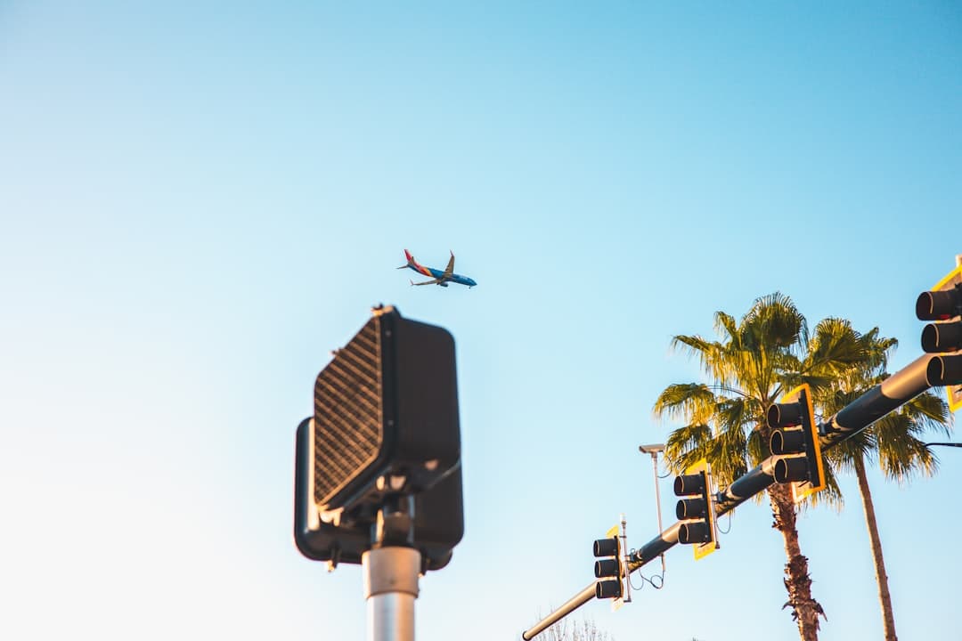 an airplane flying over a traffic light and palm trees — Photo by AK on Unsplash