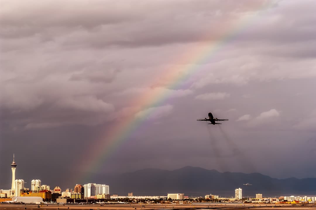 a plane flying in the sky with a rainbow in the background — Photo by Scott Fillmer on Unsplash