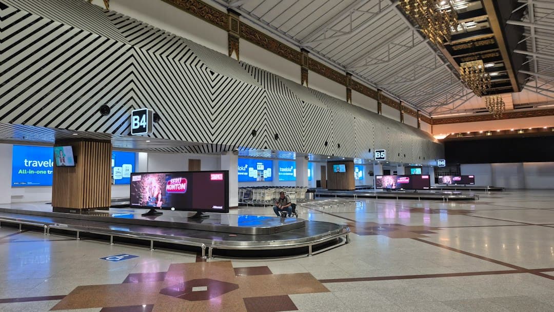 Empty airport baggage claim area with multiple conveyor belts — Photo by Edwin Petrus on Unsplash
