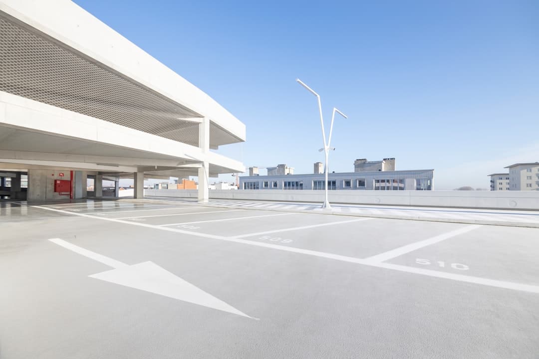 an empty parking lot with a building in the background — Photo by Jean-Philippe Delberghe on Unsplash
