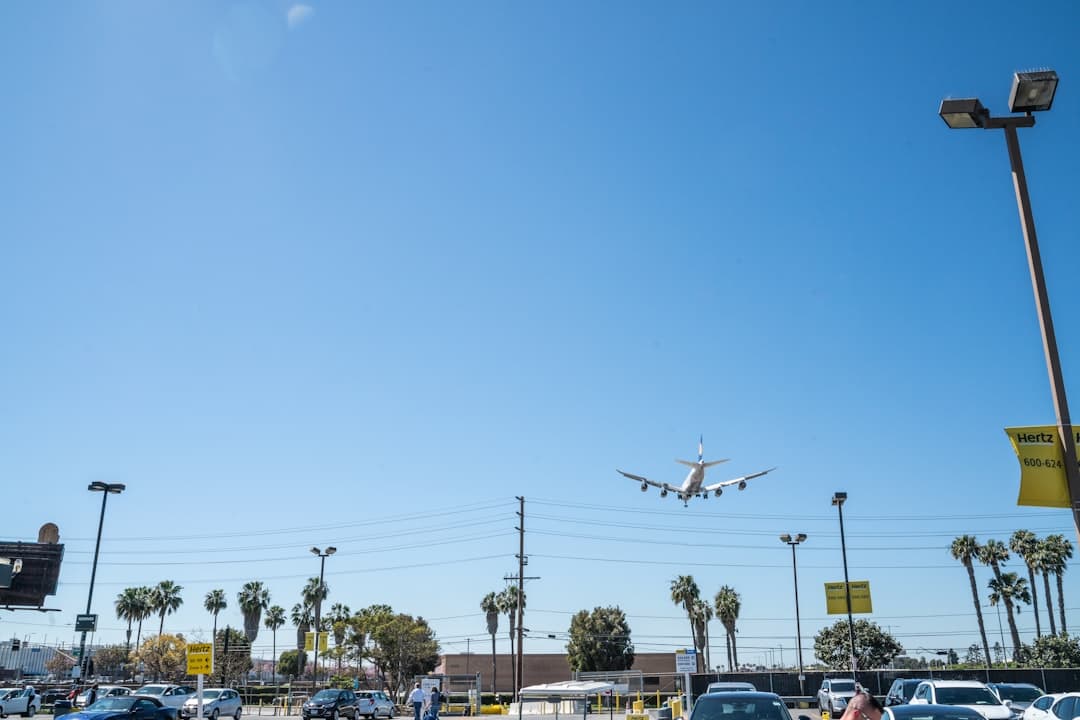 an airplane flying over a parking lot — Photo by Zack Yeo on Unsplash