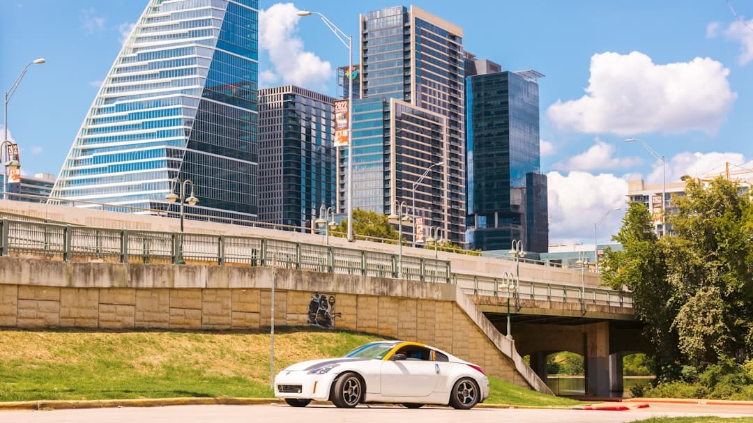 a car driving on a road with tall buildings in the background — Photo by Lewis Guapo on Unsplash