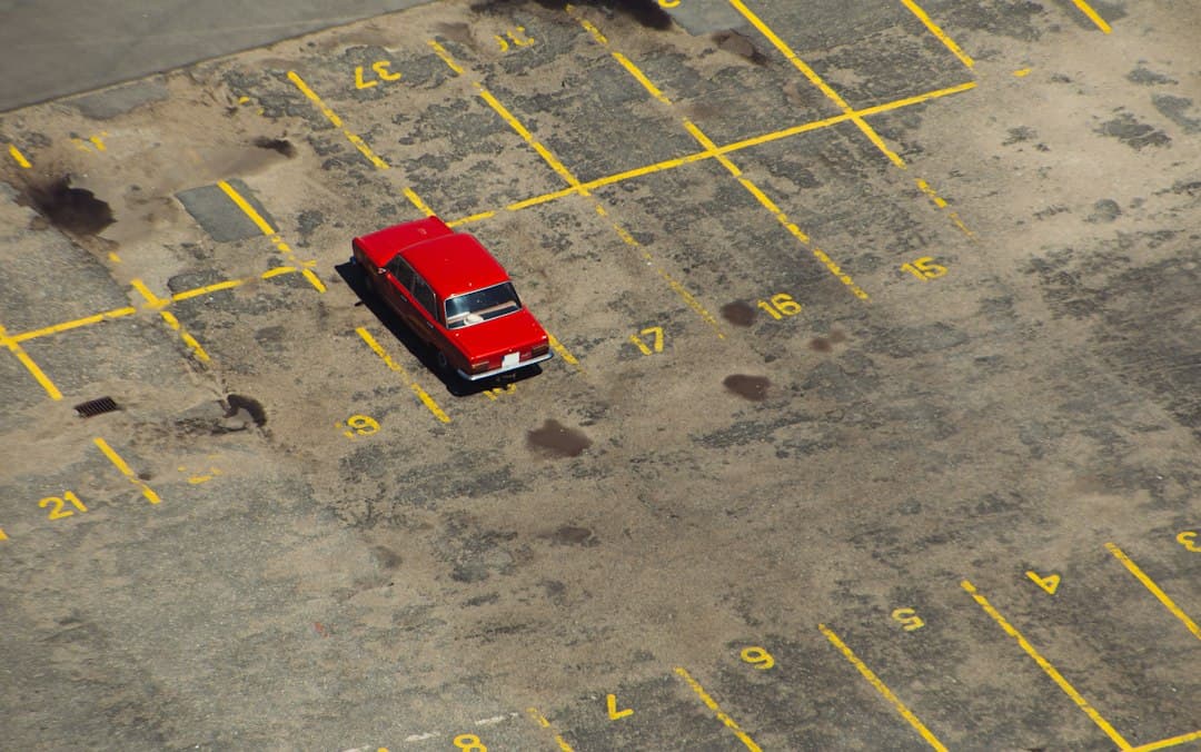 red car parked on parking lot — Photo by Krzysztof Kotkowicz on Unsplash
