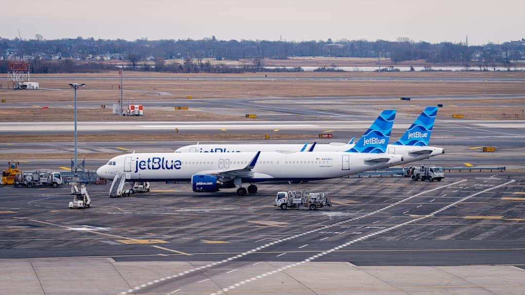 Jetblue airplane parked at airport tarmac with service vehicles — Photo by Lumin Osity on Unsplash