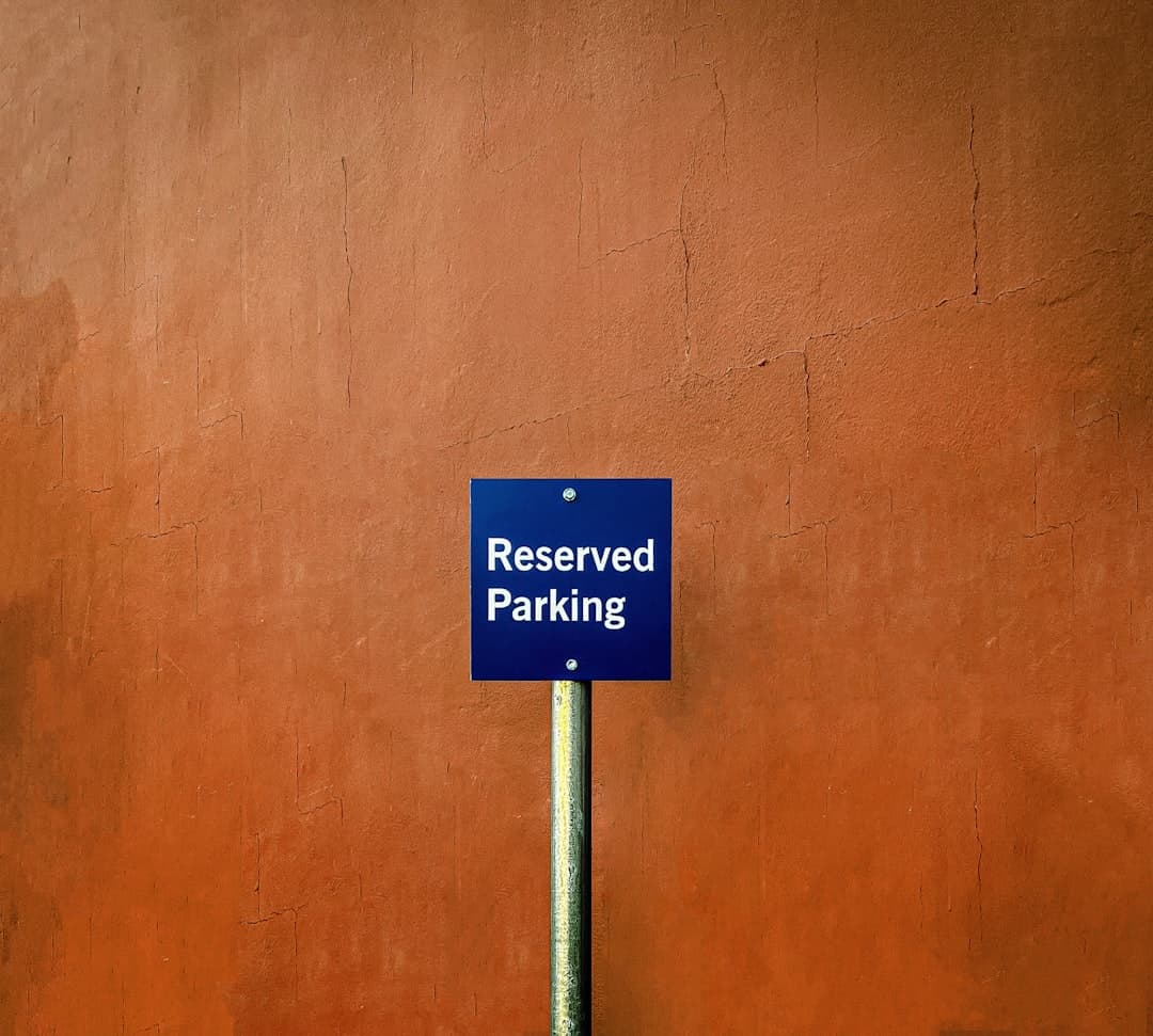 a blue sign that reads reserved parking in front of a red wall — Photo by mk. s on Unsplash