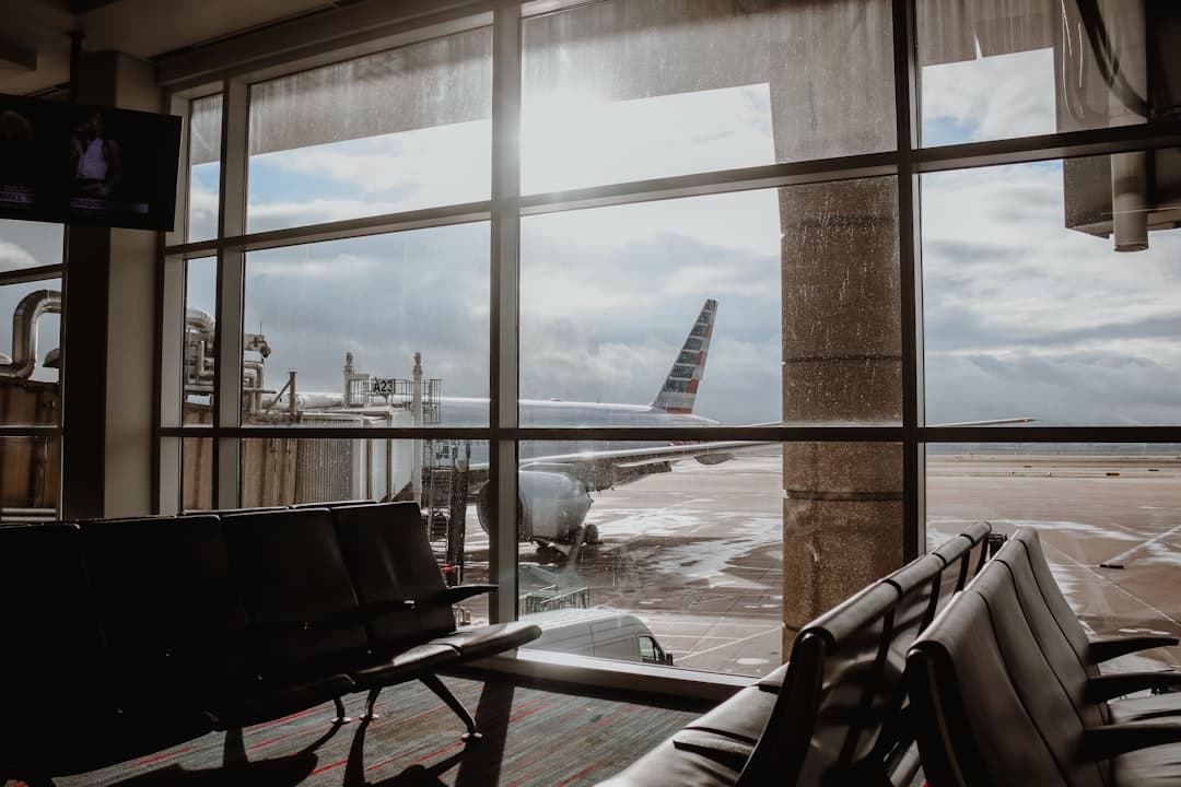 white and red plane view from glass window of waiting area — Photo by Briana Tozour on Unsplash