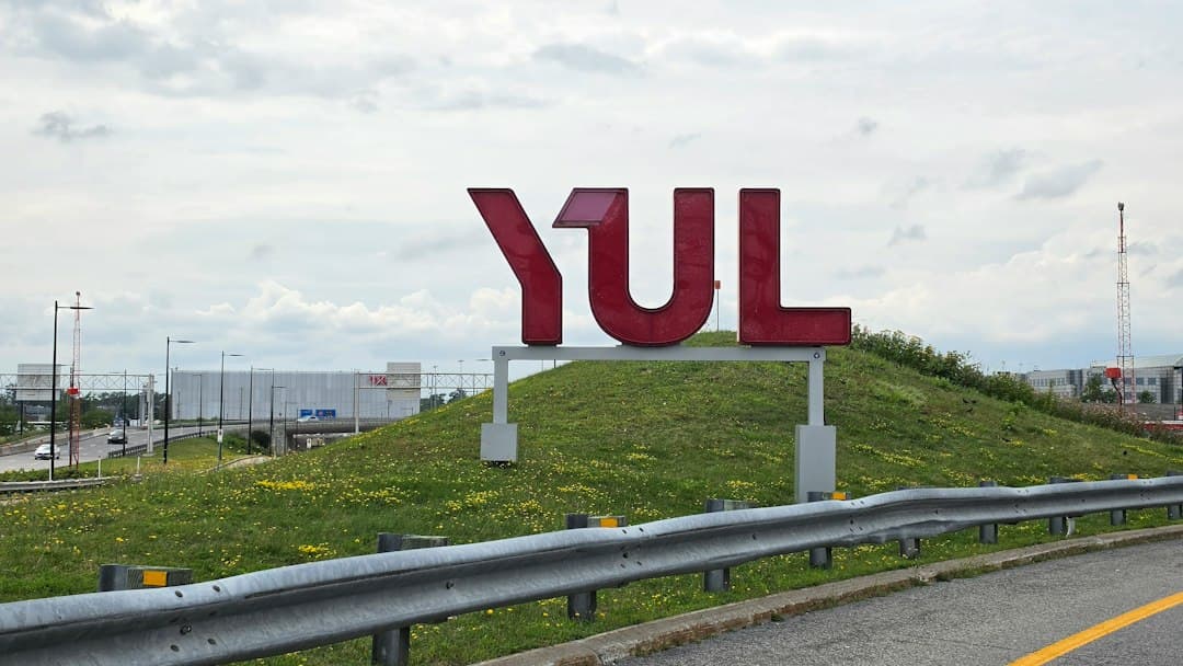 Large red YUL letters on a grassy hill beside a highway — Photo by Medad Media on Unsplash