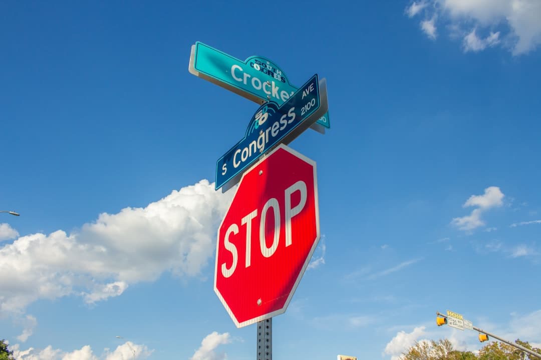 a stop sign with street signs on top of it — Photo by Roman Davis on Unsplash
