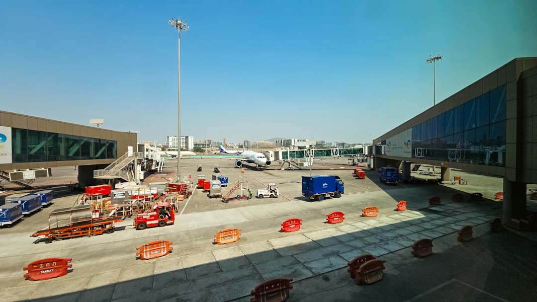 An airplane parked at an airport gate with ground support vehicles on the tarmac — Photo by Zoshua Colah on Unsplash