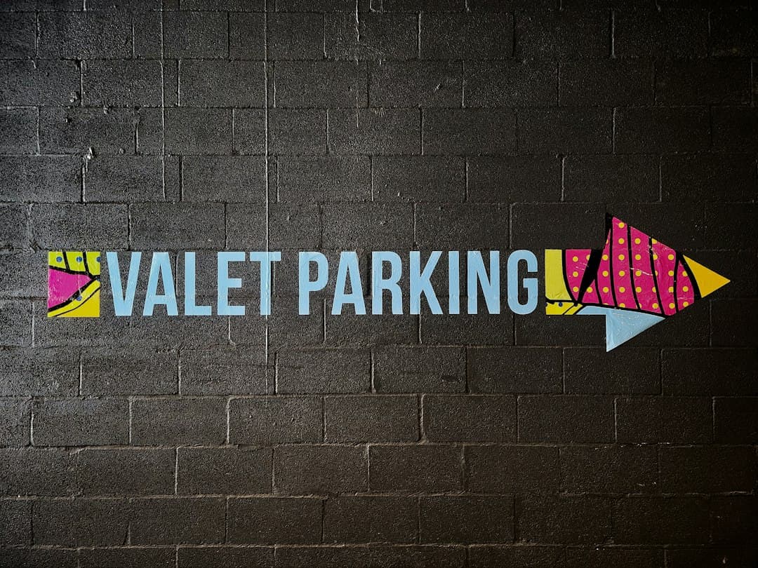 a painted sign on a brick wall that says valet parking — Photo by George Pagan III on Unsplash