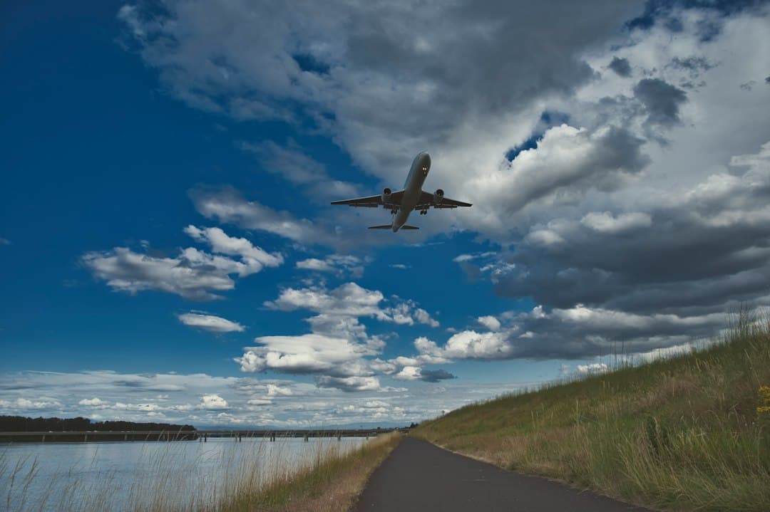 airplane flying over green grass field under blue and white cloudy sky during daytime — Photo by Kevin Butz on Unsplash