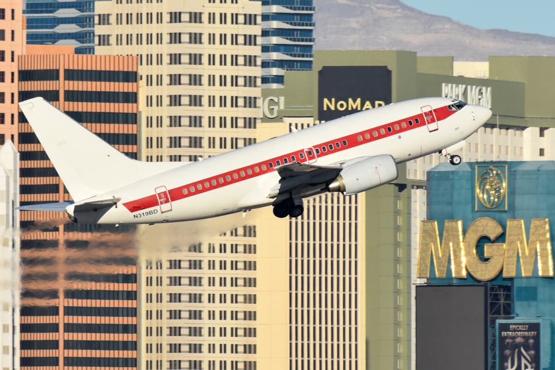 A large jetliner flying over a city with tall buildings — Photo by David Syphers on Unsplash
