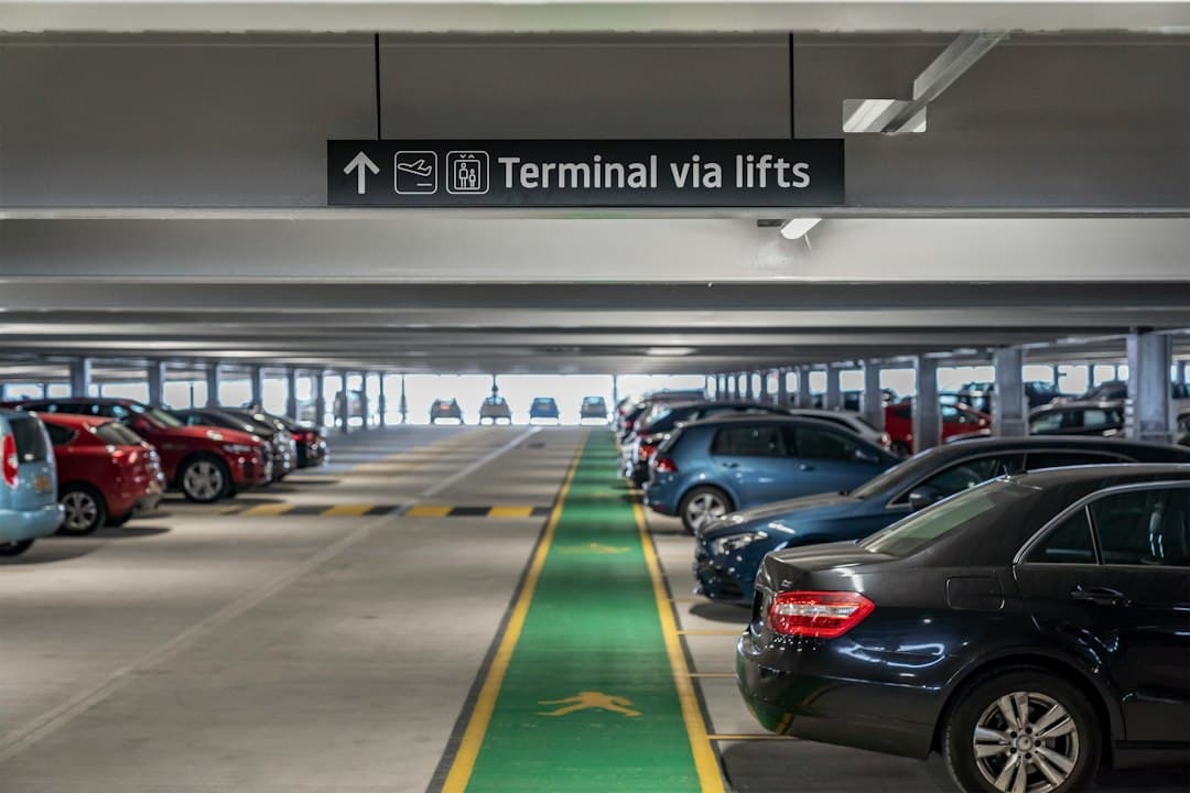 Cars parked in a multi-level parking garage with directional signage — Photo by Holiday Extras on Unsplash